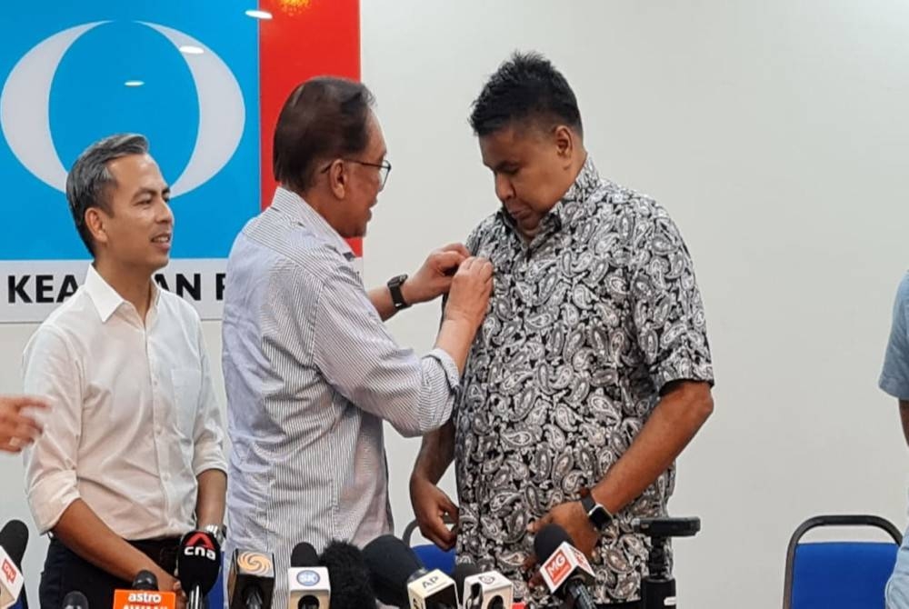 Anwar memakaikan lencana logo PKR simbolik kepada penyertaan Rais dalam PKR.