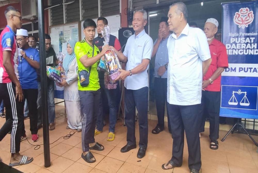 Othman (dua dari kanan) menyampaikan hamper kepada penduduk yang menyertai kejohanan anjuran PDM Putat di Jerlun pada Jumaat.