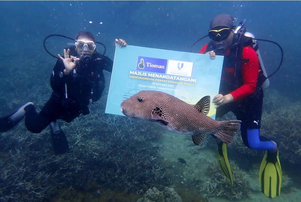 Yuserrie (kanan) dan Idros menyempurnakan majlis menandatangani MoU antara UMP dan TDA di dasar laut Pulau Tioman pada Isnin.