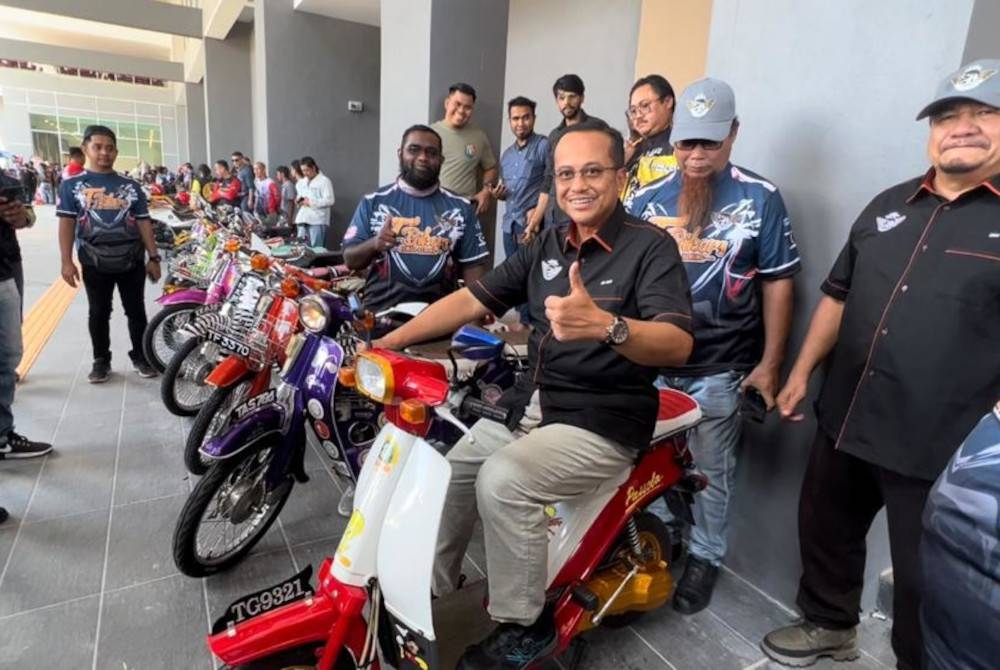 Ahmad Samsuri (tengah) cuba menaiki sebuah motosikal yang dipamerkan ketika program T-Bikers Kemah Keming 2022 - 1st Gathering, Kuala Terengganu pada Sabtu.