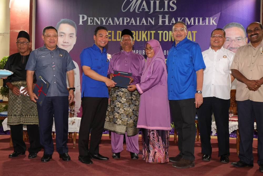 Onn Hafiz (tiga dari kiri) dan Hishammuddin (tiga dari kanan) ketika penyerahan Notis 5A kepada pasangan suami isteri pada Majlis Penyampaian Hak Milik Felda Bukit Tongkat hari ini. - Foto Bernama