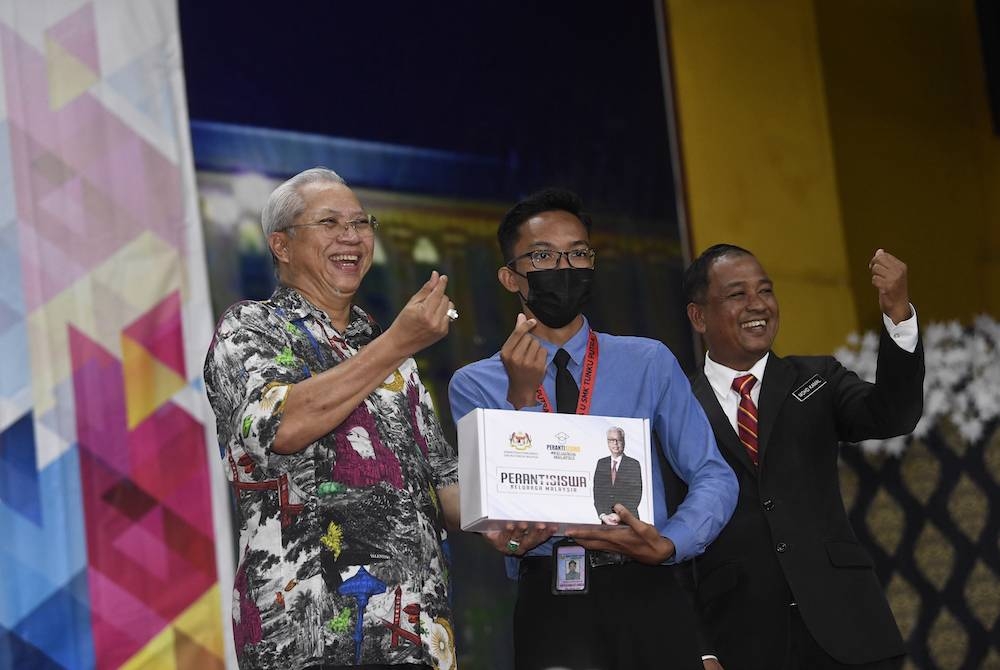 Annuar menyerahkan perantisiswa kepada Muhammad Amzar Mohd Adanan dari Sekolah Menengah Tunku Putra Langkawi pada sesi penyerahan Inisiatif Peranti Siswa Keluarga Malaysia di Kolej Vokasional Pulau Langkawi hari ini. - Foto Bernama