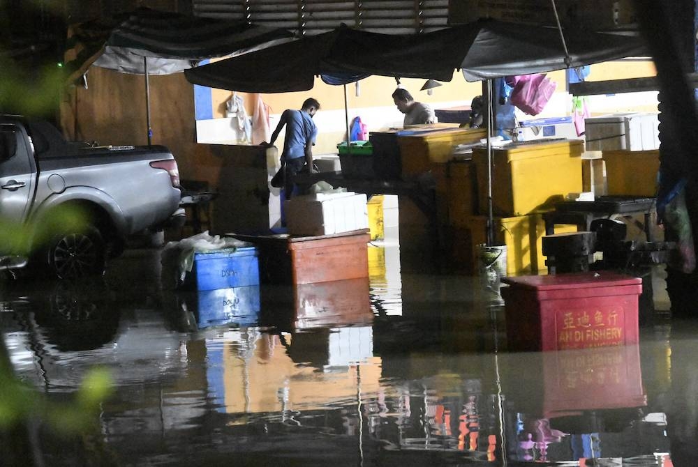 Beberapa peniaga memeriksa barangan mereka di Pasar Awam Padang Mat Sirat yang dinaiki air ketika tinjauan malam ini. Foto Bernama