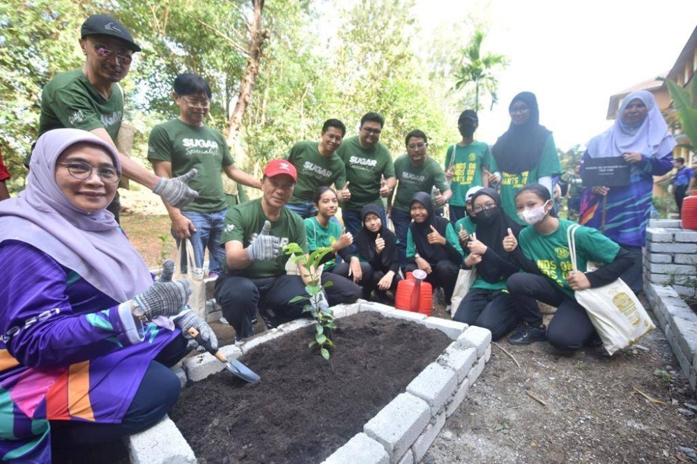 Mohamad Zuki bersama murid sekolah menanam pokok durian belanda sebagai simbolik usahasama kedua pihak untuk program kelestarian.