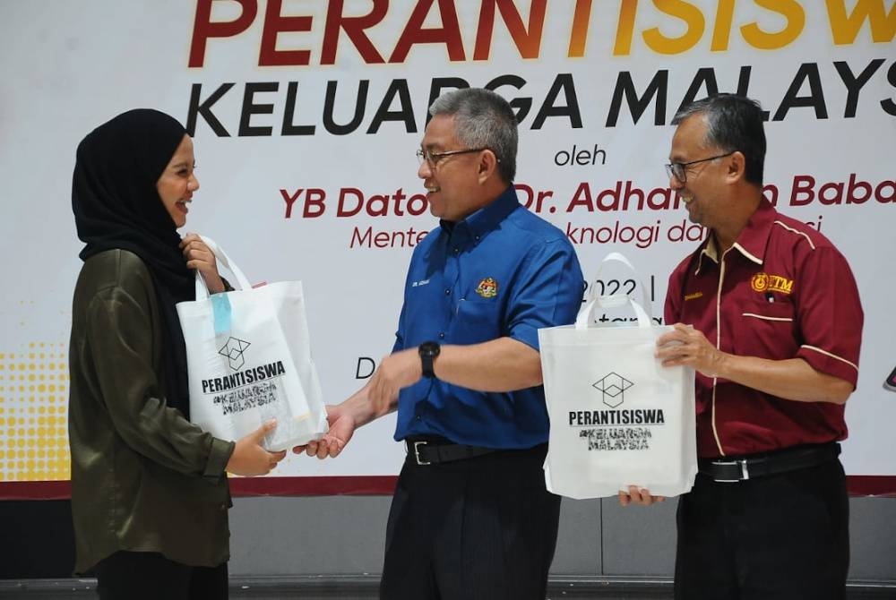 Dr Adham (tengah) menyampaikan peranti kepada salah seorang mahasiswa dalam Majlis Agihan Peranti Mahasiswa Keluarga Malaysia di UTM Skudai, Johor Bahru pada Rabu.