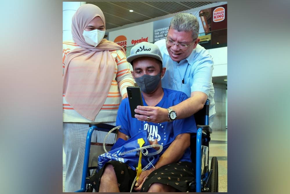 Saifuddin membantu Azhar berhubungan dengan kakaknya di Kuantan semasa menyambut kepulangan rakyat Malaysia yang mengalami serangan strok di Korea Selatan baru-baru ini di KLIA pada Rabu. - Foto Bernama