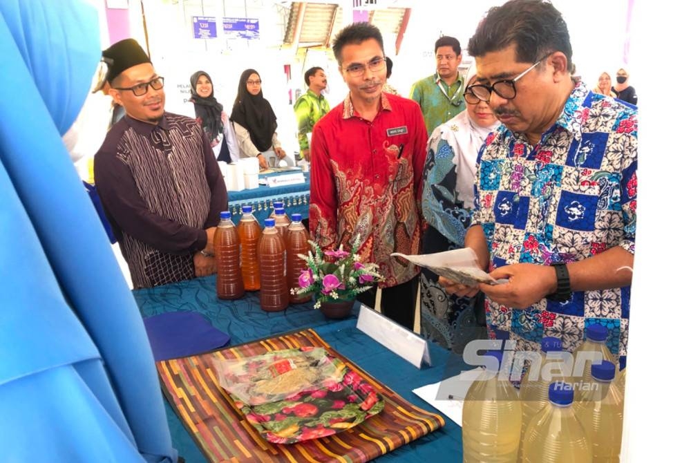 Md Alwi (kanan) melihat ikan produk ikan talapia di gerai pameran di SMK Kok Lanas, Kota Bharu pada Khamis.