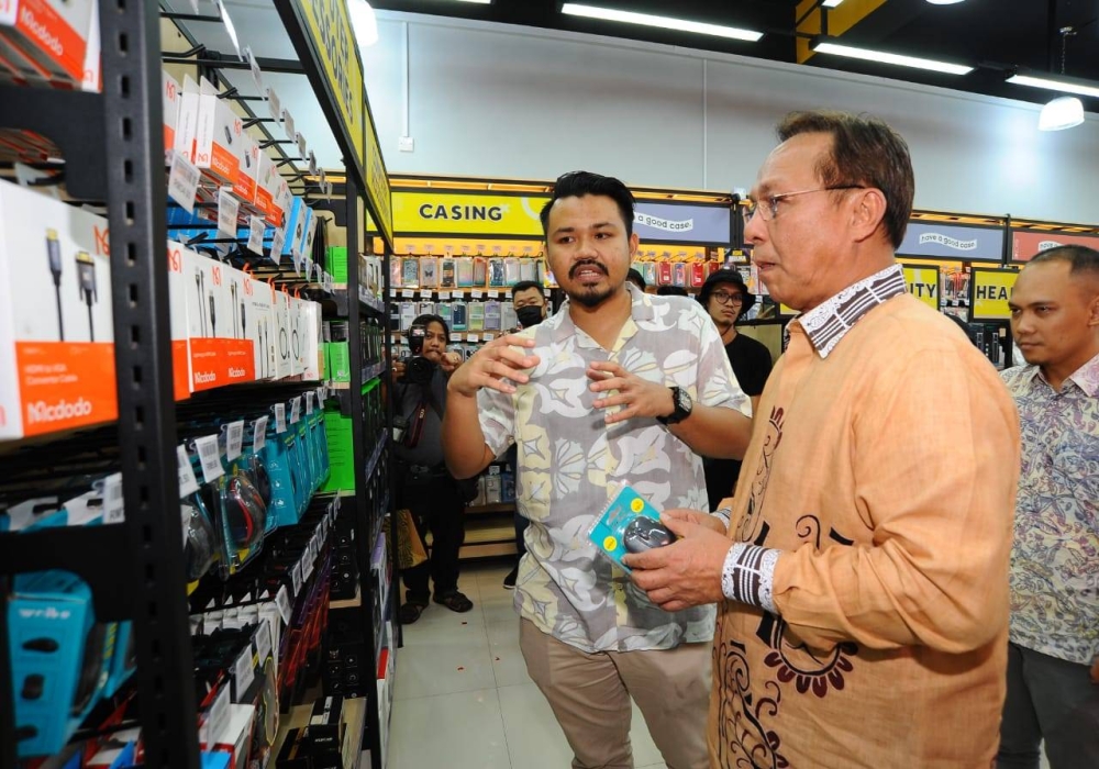 Hasni (kanan) diberi penerangan oleh Muhamad Farouk Hassanain Hashim mengenai jualan gajet sempena pembukaan rasmi cawangan baharu Al Ikhlas Gadjet di Larkin Sentral, Johor Bahru pada Sabtu.