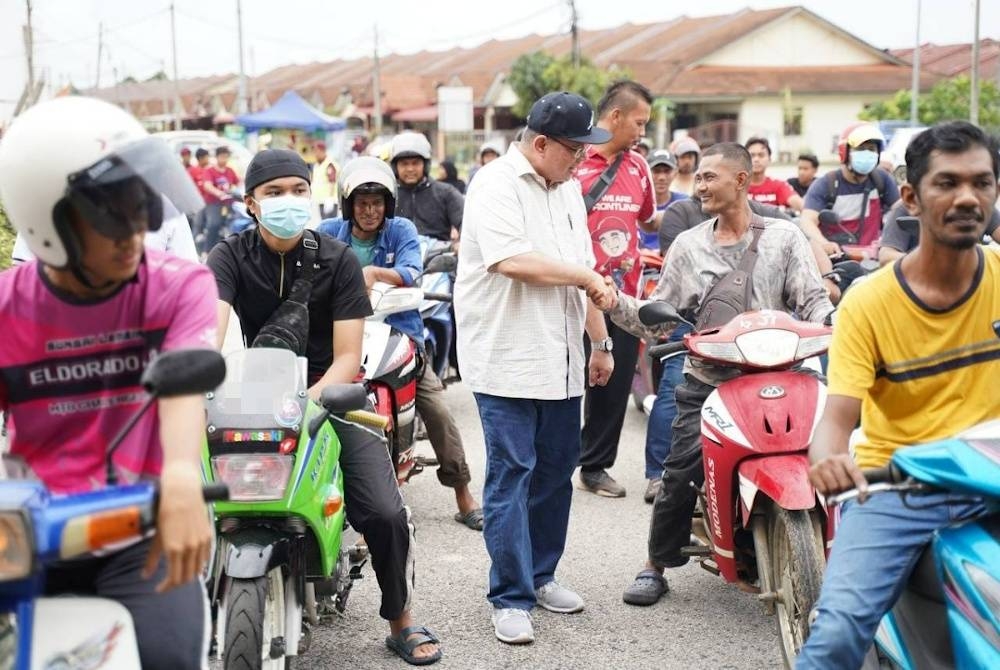 Saifuddin beramah mesra dengan pengunggang motosikal pada program minyak petrol percuma yang dikendalikan Hasif Upin di sebuah stesen minyak di Balok di sini pada Sabtu.