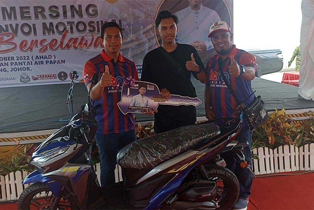 Muhammad Syukri (kiri) bergambar bersama pemenang cabutan bertuah iaitu sebuah motosikal pada program Mersing Konvoi Motosikal Berselawat pada Ahad.