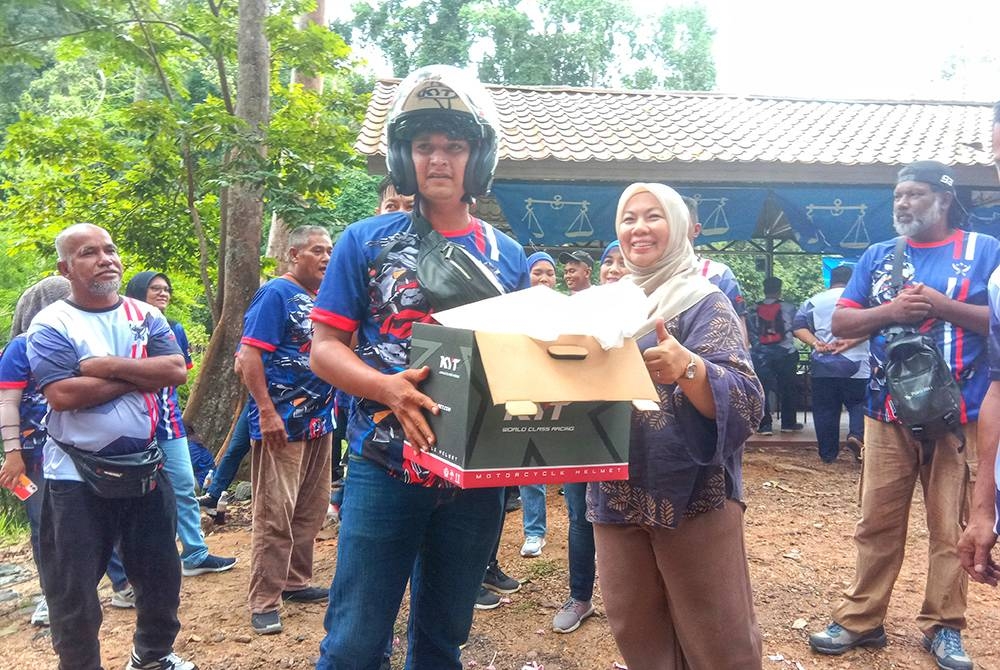 Shahaniza (kanan) menyampaikan hadiah cabutan kepada peserta bertuah pada program Young Bikers Gathering@Lubuk Yu.