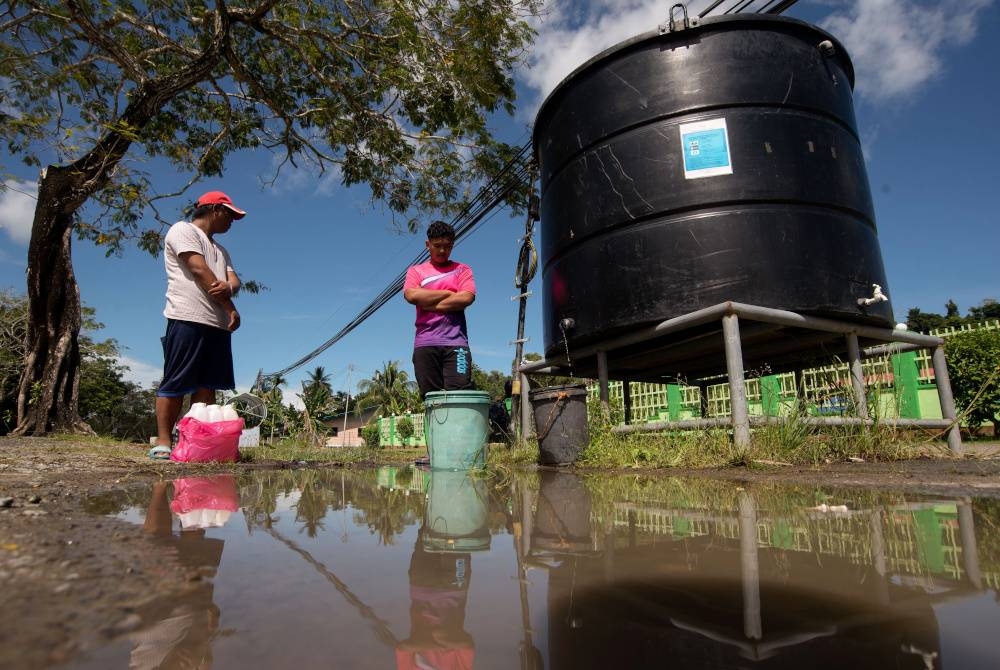 Penduduk setempat mengambil bekalan air bersih daripada tangki statik yang disediakan oleh JBA Labuan di Kampung Lubok Temiang hari ini. - Foto Bernama