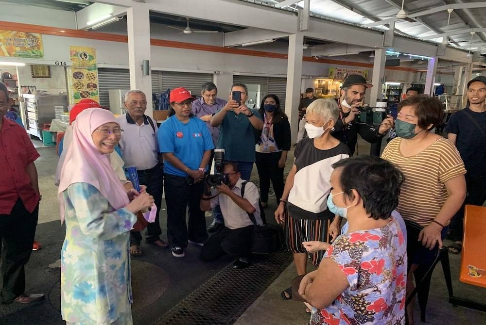 Dr Wan Azizah (kiri) ketika menyantuni penduduk di Medan Selera Desa Tun Razak, Kuala Lumpur pada Khamis.