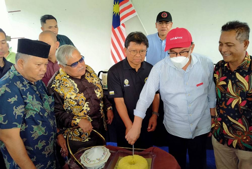 Anwar (dua dari kanan) bersama Asmuni (tengah) memotong pulut ketika Program Ramah Mesra Bersama Veteran Pesara Tentera di Dewan Orang Ramai RPT Batu 10 Chepor di sini pada Khamis.