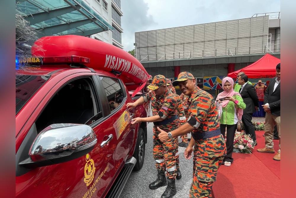 Mohammad Hamdan menampal pelekat MTL RED Team ke atas jentera pasukan itu. Turut hadir, Pengarah Bahagian Operasi Kebombaan dan Penyelamat Malaysia, Datuk Nor Hisham Mohamad.