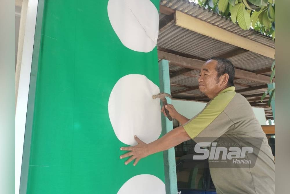 Ghani memasang bendera Pas pada dinding markas di Kampung Batu Hampar.