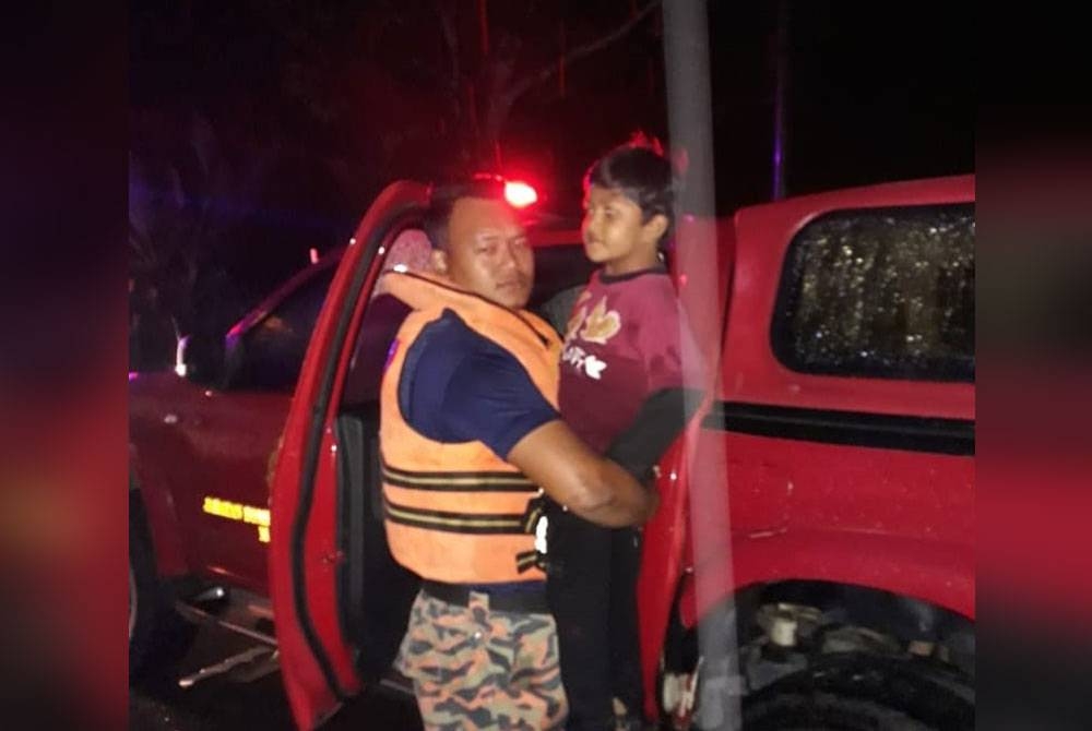 Anggota bomba menyelamatkan kanak-kanak yang terjejas banjir di Baling pada Jumaat.