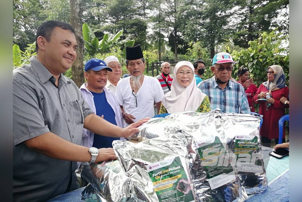 Dr Wan Azizah (dua dari kanan) menyerahkan baja kepada penduduk PA Sri Sabah pada Sabtu.