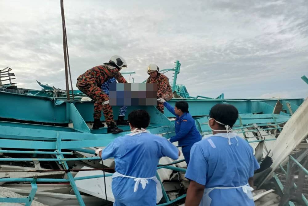 Bomba mengeluarkan salah seorang mangsa yang terbabit dalam nahas runtuhan kren gantri di Lumut. - Foto Ihsan bomba