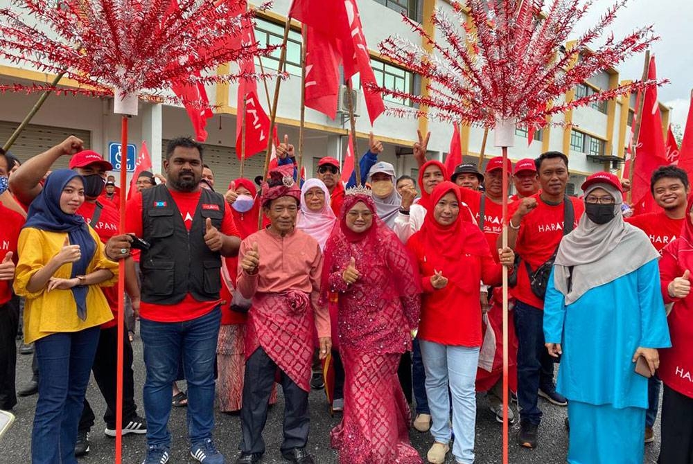 Mohd Sailan dan Nur Mizatulamni (tengah) bersama penyokong PH di Pusat Penamaan Calon Parlimen Simpang Renggam di Dewan Muafakat Majlis Daerah Simpang Renggam pada Sabtu.