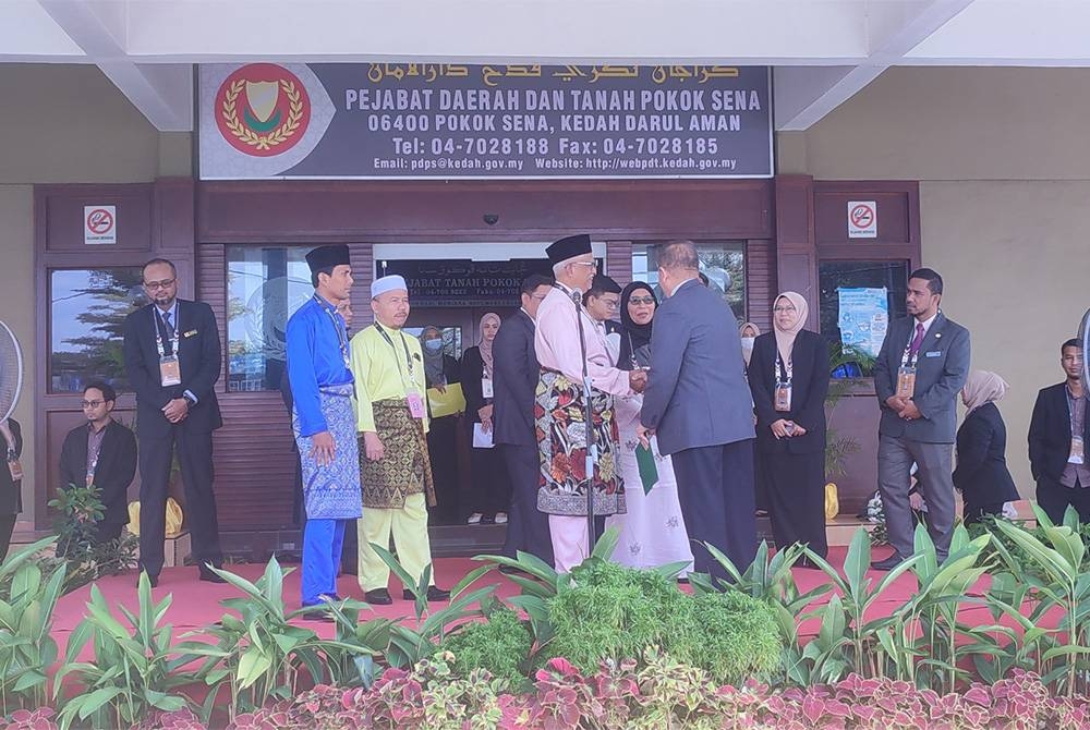 Mahfuz (tengah) beramah mesra dengan Pegawai Pengurus Bahagian Pilihan Raya Parlimen Pokok Sena, Ahmad Bawadir Abdul Ghani selepas selesai sesi penamaan calon di Pusat Penamaan Calon Pokok Sena di Pejabat Daerah dan Tanah Pokok Sena, di sini, pada Sabtu.