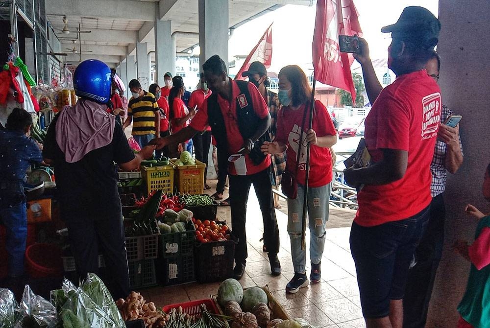 Tinagaran (tiga dari kanan) ketika mengedarkan risalah manifesto di Pasar Pekan Rantau pada Ahad.