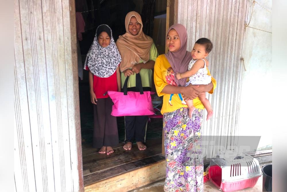 Norasila (kanan) bersama bayi dan adik-beradik terkepung susulan banjir sejak Khamis lalu.