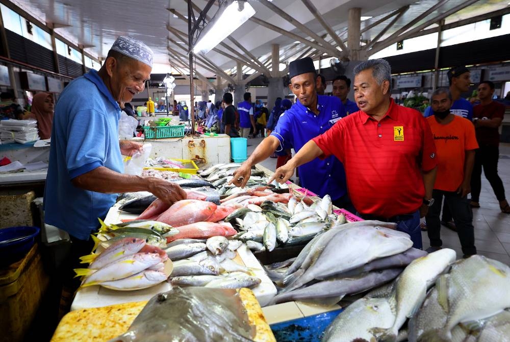 Ahmad (kiri) beramah mesra bersama dengan peniaga di Pasar Binjai Kemaman pada Ahad. - Foto Bernama