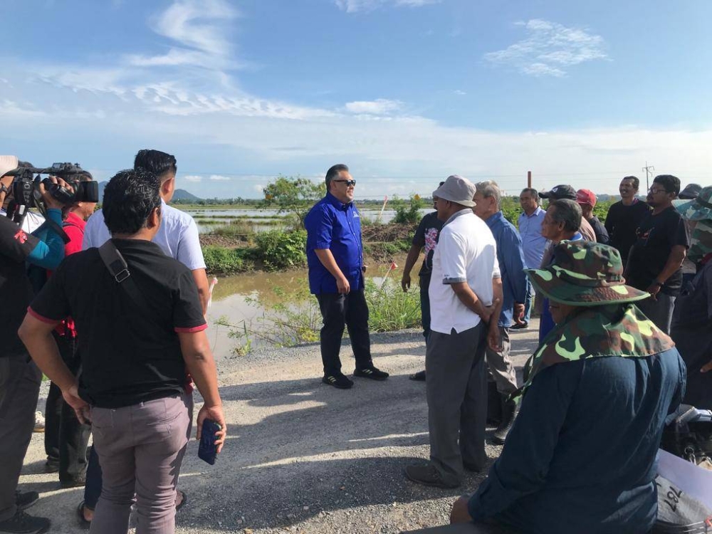 Rozabil (tengah) mendengar rintihan pesawah mengenai masalah pengaliran air di Kampung Bakong, Arau pada Isnin.