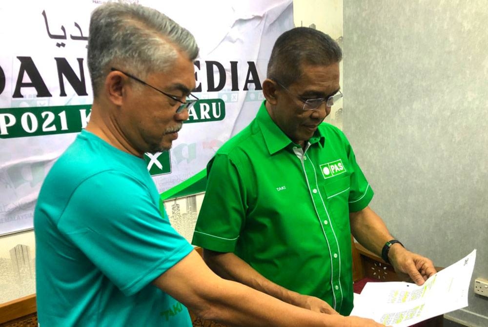 Takiyuddin (kanan) meneliti Perlembangaan Pas semasa ditemui di Pejabat Parlimen Kota Bharu di Kota Bharu pada Isnin.