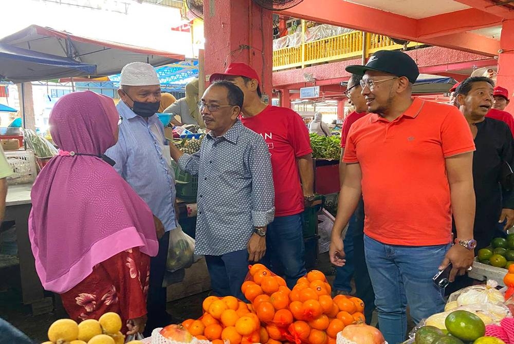 Mohamad Suparadi (tengah) beramah mesra dengan orang ramai semasa program turun padang di Pasar Besar Tanah Merah pada Selasa.