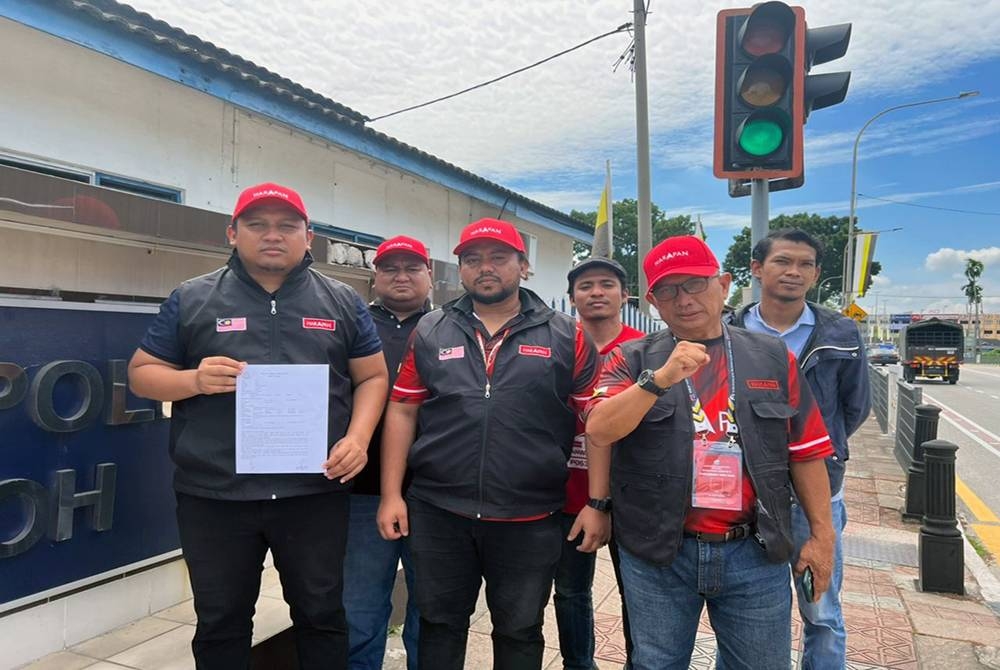 Ashraf (kiri) menunjukkan laporan polis polis yang dibuat terhadap Razman di hadapan IPD Ipoh di sini pada Selasa.