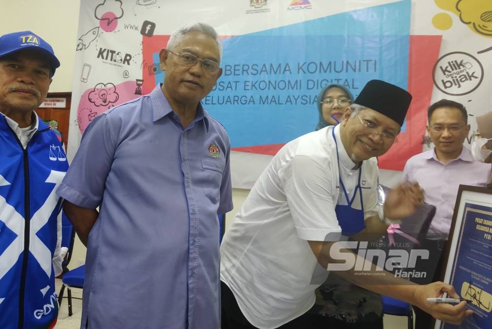 Annuar (kanan) menandatangani plak perasmian pada Majlis Hari Bersama Komuniti Pusat Ekonomi Digital Keluarga Malaysia di Felda Bukit Cherakah di Kuala Selangor pada Selasa.