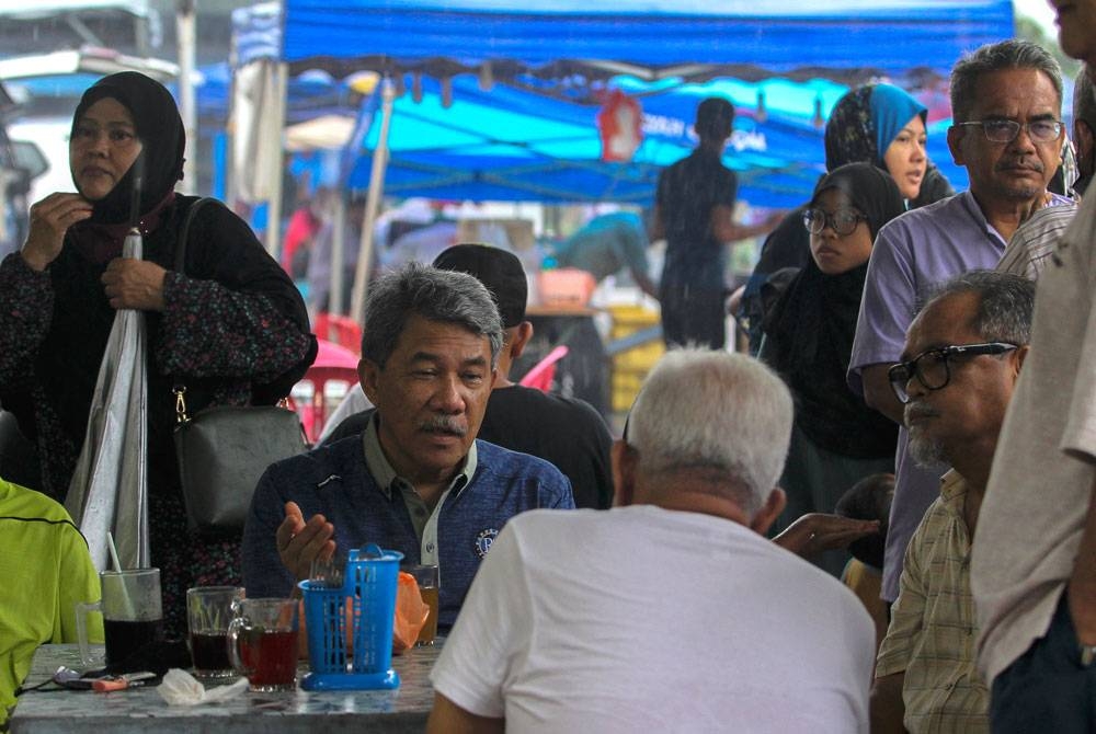 Mogamad (duduk dua dari kiri) beramah mesra dengan orang ramai di Pasar Malam TTJ