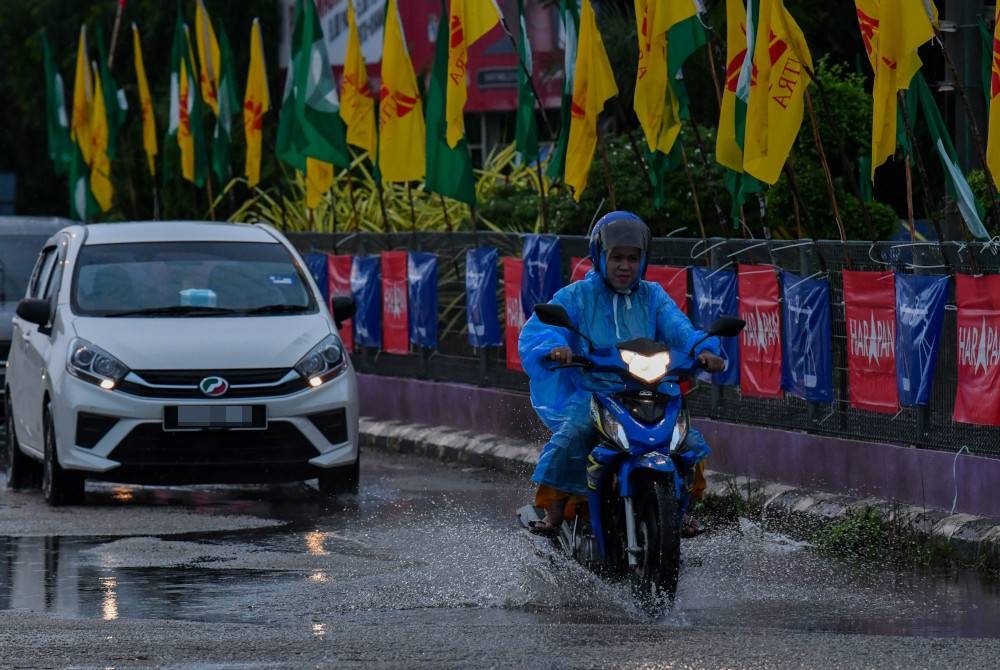 Pengguna jalan raya melalui deretan bendera pelbagai parti politik berikutan hujan ketika tinjauan di Rantau Panjang Ahad. - Foto Bernama