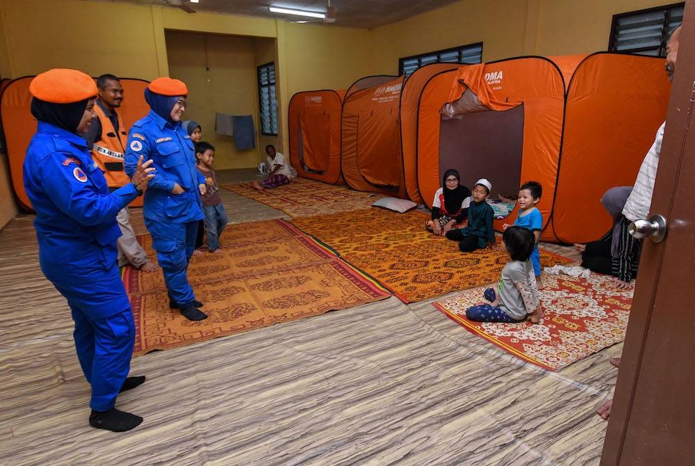 Anggota Angkatan Pertahanan Awam Malaysia (APM) Rantau Panjang beramah mesra dengan mangsa banjir yang ditempatkan di PPS Sekolah Kebangsaan Gual To&#039;Deh. - Foto Bernama