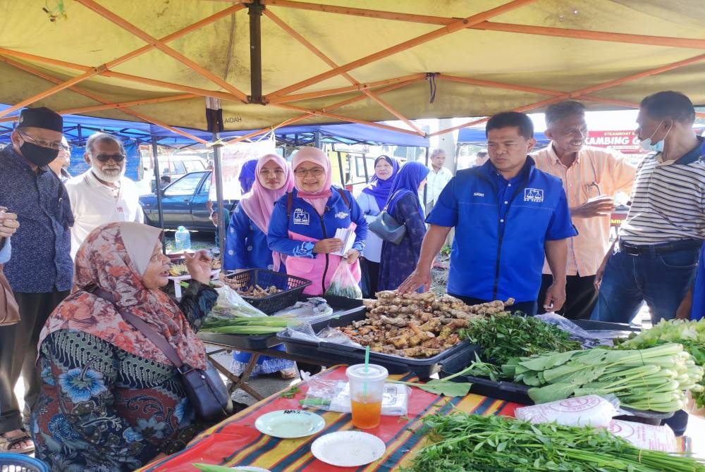 Nawi (tiga, kanan) bertanya khabar peniaga ketika turun berkempen di pasar pagi Kampung Alor Lintah, di sini.