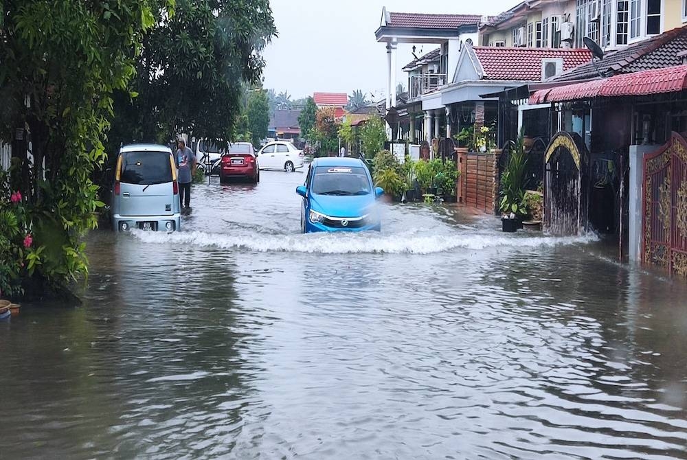 Sebuah kenderaan dilihat melalui kawasan perumahan di Meru dinaiki air pada Khamis.