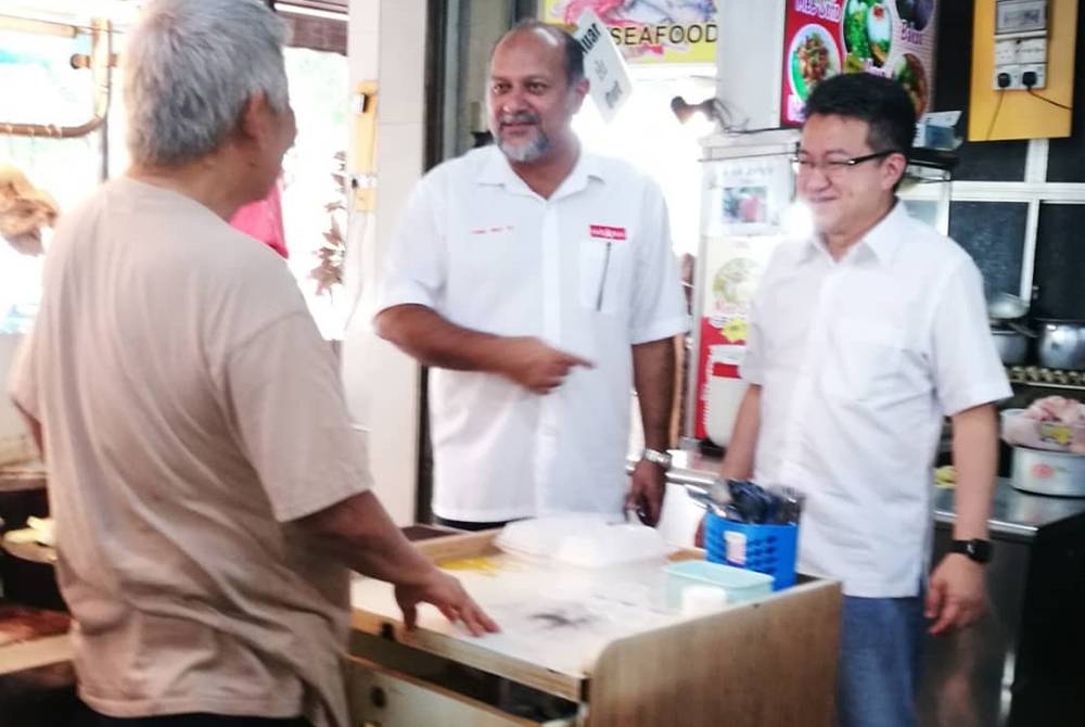 Chin Tong (kanan) dan Gobind (tengah) menyantuni seorang pengundi di Iskandar Puteri pada Sabtu.