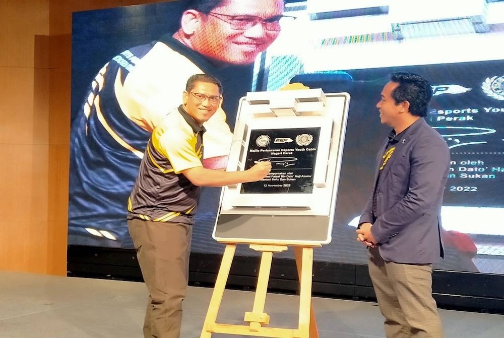 Ahmad Faizal (kiri) sambil disaksikan Muhammad Naim Al-Amin menyempurnakan Pelancaran E-Sports Youth Cabin Perak di sebuah hotel di sini pada Sabtu.