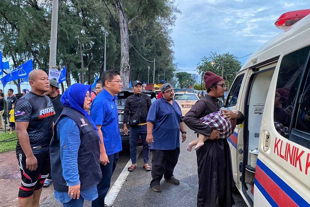 Tuminah (dua, kiri) bersama calon BN Tangga Batu, Datuk Lim Ban Hong (tiga, kiri) melihat bayi itu menaiki ambulans.