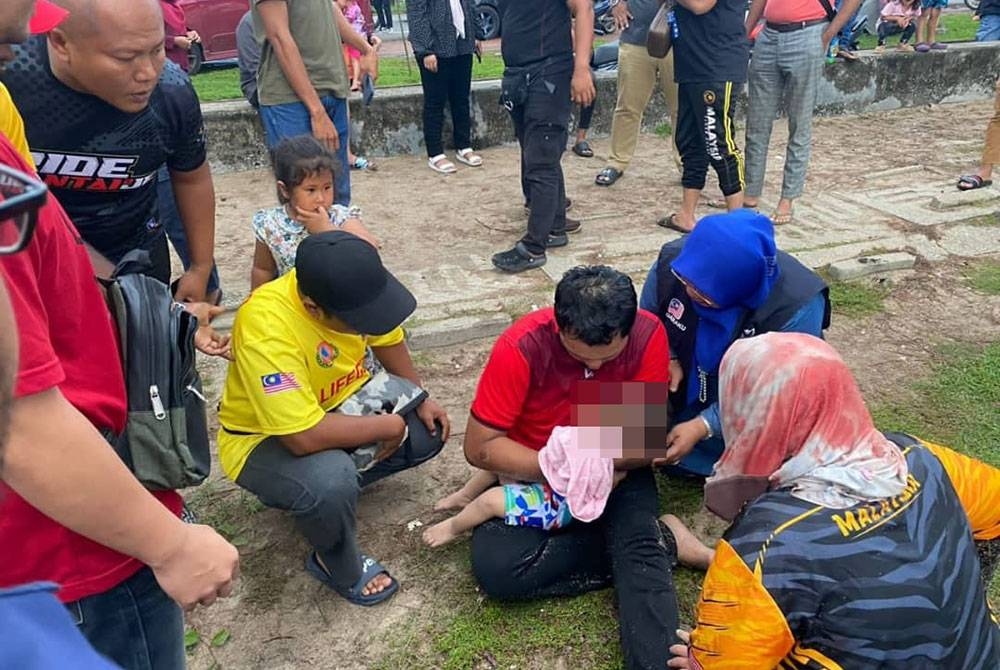 Tuminah (dua, kanan) bersama bapa bayi terbabit yang sedang meriba bayinya yang mengalami kecederaan.