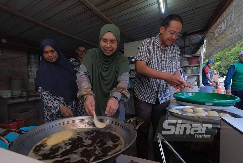 Samsuri dan isteri, Tuan Faezah memasak sendiri roti binjai ketika singgah beramah mesra dengan penduduk di kedai berkenaan di Kampung Buluh, di sini, petang Sabtu.