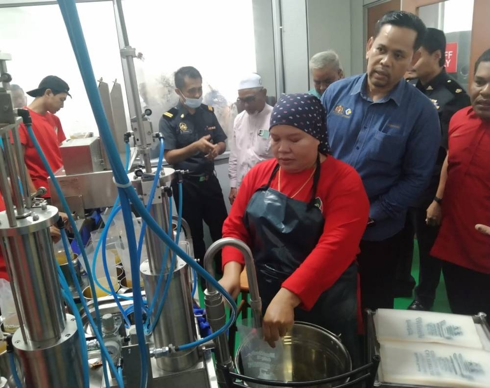 Saharuddin (kanan) ketika memeriksa proses pembungkusan minyak masak di Bunian Oil, Dungun pada Ahad.