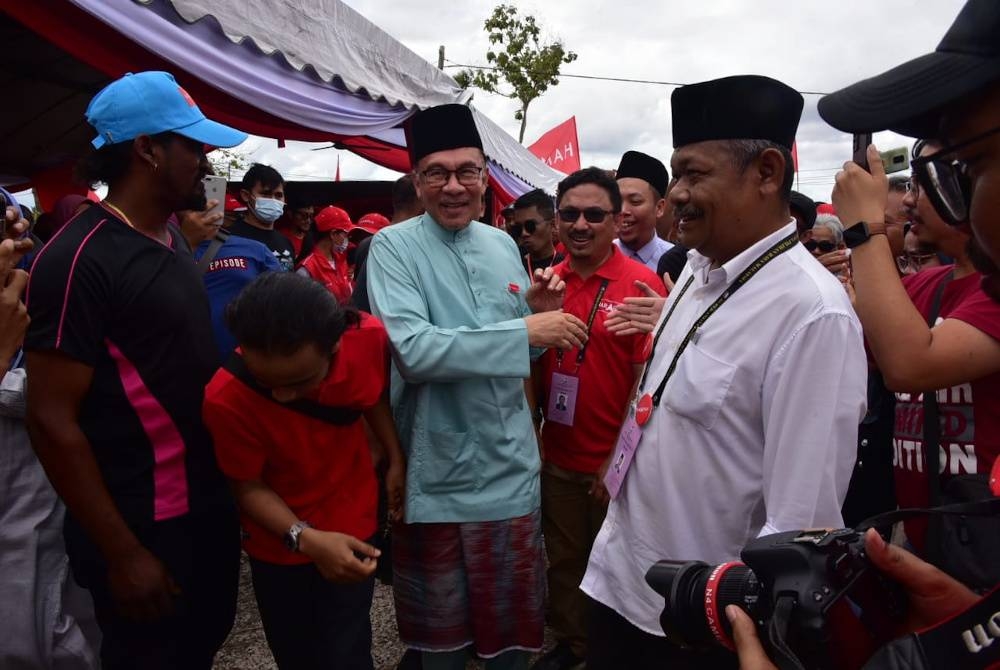 Anwar (tengah) bersalaman dengan tetamu Kenduri Rakyat PH di Kampung Mengkuang Layar pada Ahad.