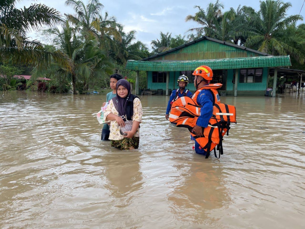 Anggota Angkatan Pertahanan Awam (APM) membantu penduduk setempat berpindah dari Kampung Sri Gambut, Pekan Nanas ke PPS di SK Melayu Raya, Pontian, pada Ahad.