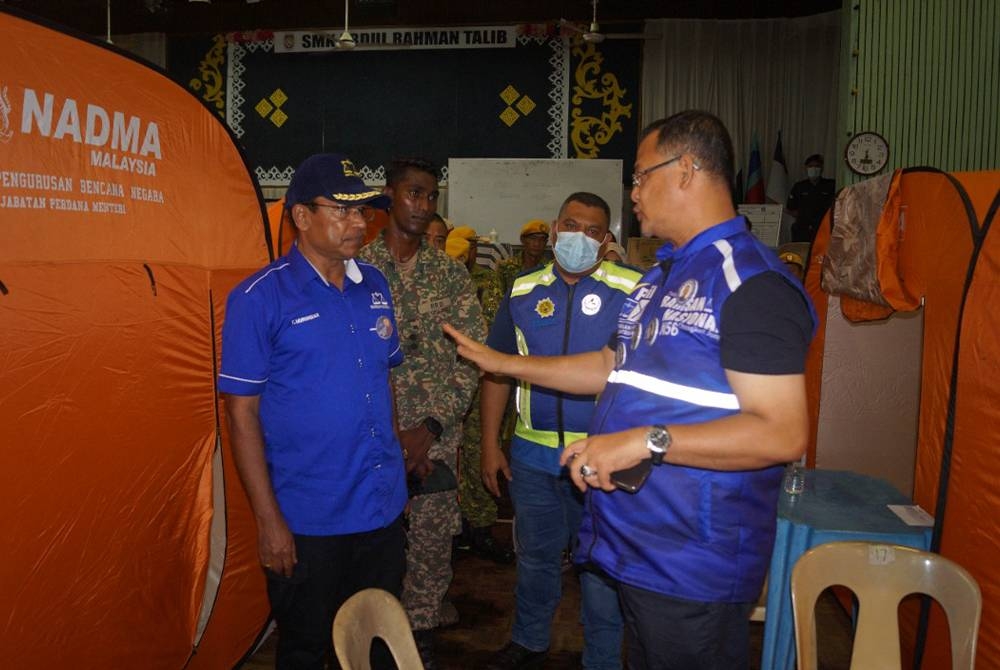 Murugiah (kiri) diberi penerangan mengenai penempatan mangsa banjir di Dewan Serbaguna Changkat Jong.