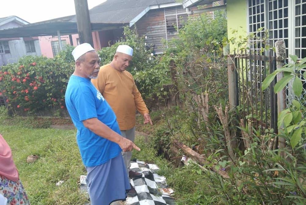 Amran (kiri) menunjukkan sistem saliran dan perparitan yang terlalu sempit di kawasan perumahan tersebut menyebabkan berlakunya banjir kilat.