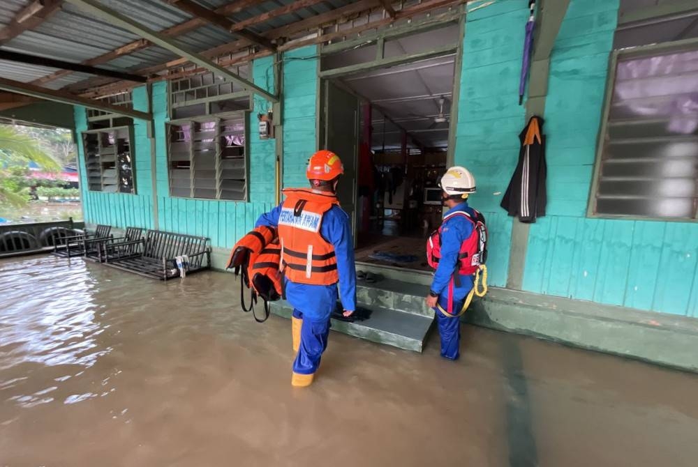 Anggota Angkatan Pertahanan Awam (APM) membantu penduduk setempat berpindah dari Kampung Sri Gambut, Pekan Nanas ke PPS di SK Melayu Raya, Pontian pada Ahad