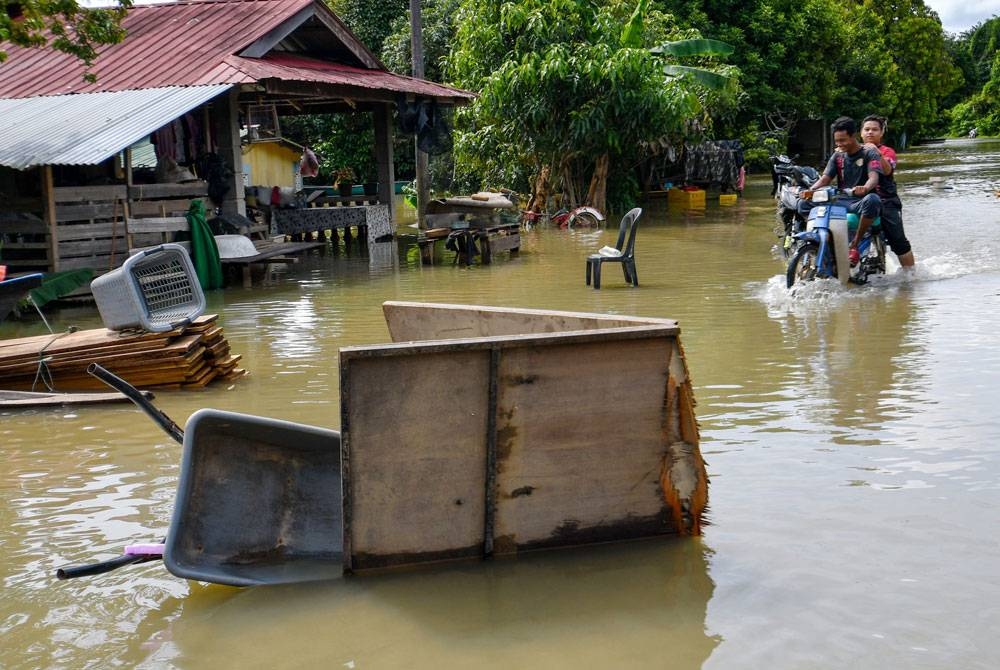 Penduduk meredah banjir menggunakan motosikal ketika tinjauan di Kampung Tersang, Rantau Panjang hari ini. - Foto Bernama